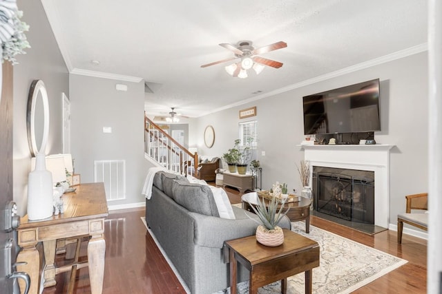 living room with hardwood / wood-style flooring, ceiling fan, and ornamental molding