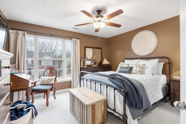 bedroom with a textured ceiling, light colored carpet, and ceiling fan