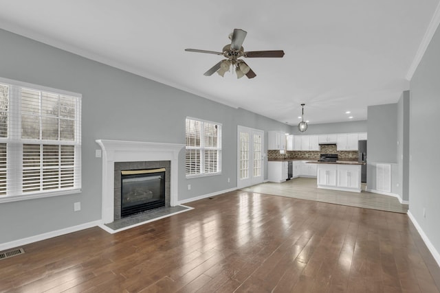 unfurnished living room featuring a tile fireplace, ceiling fan, and light wood-type flooring