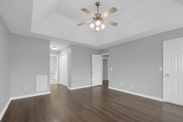 unfurnished room with a raised ceiling, dark hardwood / wood-style floors, and ceiling fan