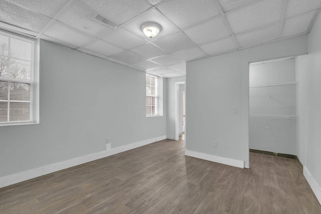 spare room featuring dark hardwood / wood-style flooring and a drop ceiling