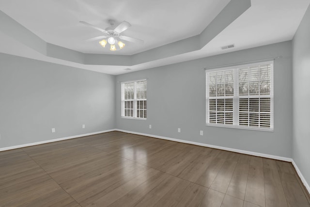 empty room featuring hardwood / wood-style floors, ceiling fan, and a tray ceiling