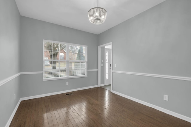 unfurnished room with dark wood-type flooring and an inviting chandelier