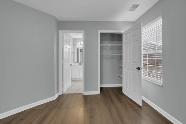 unfurnished bedroom featuring hardwood / wood-style flooring, ensuite bath, and a closet