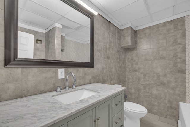 bathroom featuring tile walls, vanity, and toilet