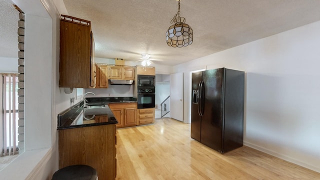 kitchen with sink, hanging light fixtures, a textured ceiling, light hardwood / wood-style floors, and black appliances