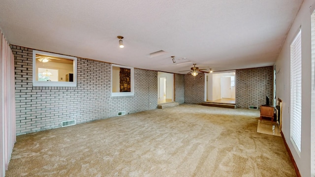 unfurnished living room featuring light colored carpet, brick wall, a textured ceiling, and a wood stove