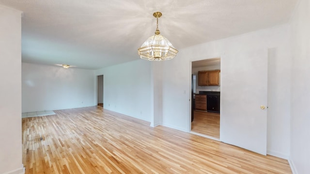 empty room featuring an inviting chandelier and light hardwood / wood-style flooring