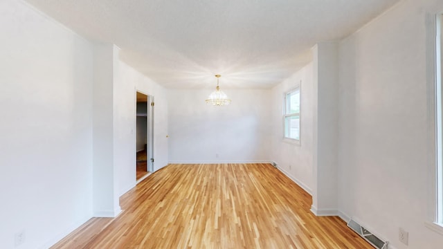 spare room with an inviting chandelier and light hardwood / wood-style flooring