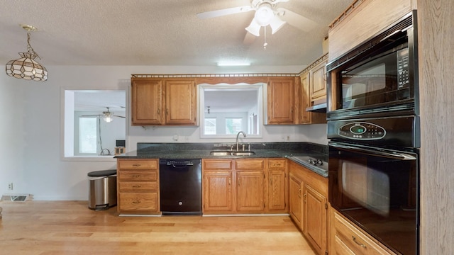 kitchen with sink, light hardwood / wood-style flooring, black appliances, a textured ceiling, and decorative light fixtures