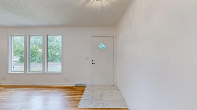 foyer entrance featuring a textured ceiling and light hardwood / wood-style flooring