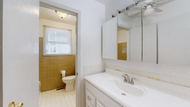 bathroom with tile patterned floors, vanity, toilet, and tile walls