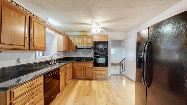 kitchen featuring sink, black appliances, a textured ceiling, dark stone counters, and light wood-type flooring