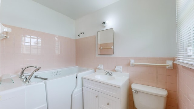 bathroom with a tub to relax in, vanity, toilet, and tile walls