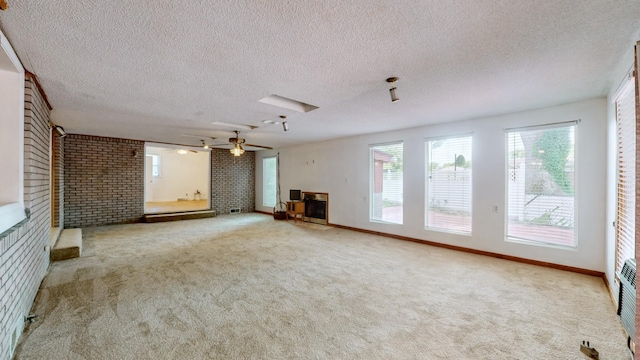 unfurnished living room with light carpet, a textured ceiling, and brick wall