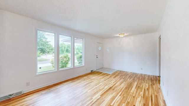 spare room featuring light hardwood / wood-style floors and a textured ceiling