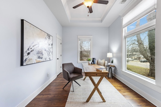 home office with a tray ceiling, dark wood-type flooring, and ceiling fan