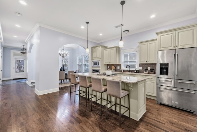 kitchen featuring light stone counters, a kitchen island, cream cabinetry, and appliances with stainless steel finishes