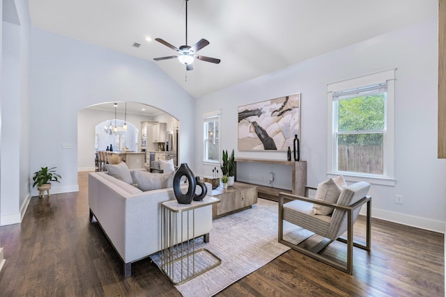 living room featuring lofted ceiling, ceiling fan with notable chandelier, and dark wood-type flooring