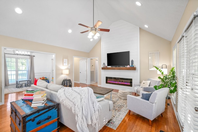 living room with ceiling fan, high vaulted ceiling, and light wood-type flooring