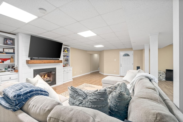 living room featuring a drop ceiling, light tile patterned floors, and built in shelves