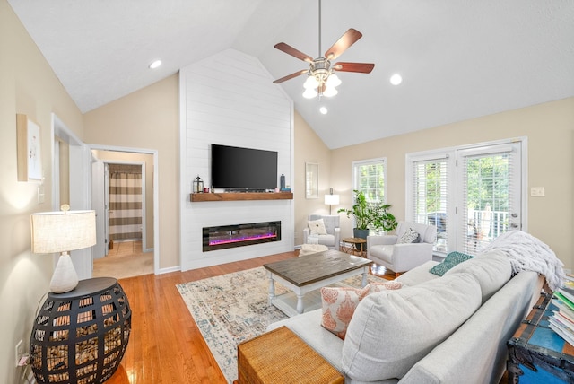 living room featuring light hardwood / wood-style flooring, high vaulted ceiling, a large fireplace, and ceiling fan