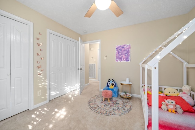 bedroom featuring ceiling fan, light colored carpet, and a textured ceiling