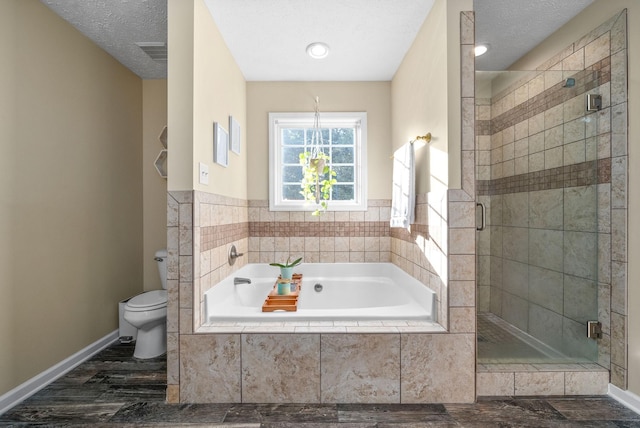 bathroom featuring toilet, separate shower and tub, and a textured ceiling