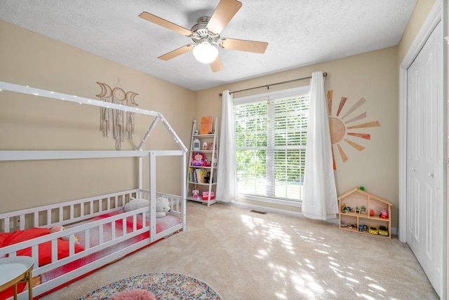 carpeted bedroom featuring ceiling fan, a closet, and a textured ceiling