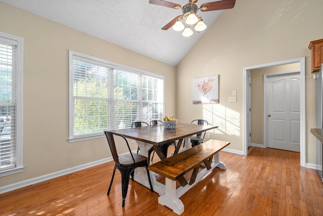 dining room with ceiling fan, lofted ceiling, a textured ceiling, and light wood-type flooring