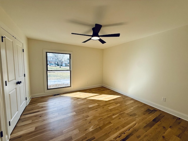 unfurnished bedroom featuring visible vents, ceiling fan, baseboards, and wood finished floors