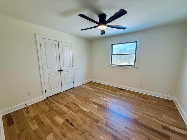 unfurnished bedroom featuring a ceiling fan, visible vents, light wood-style floors, and baseboards