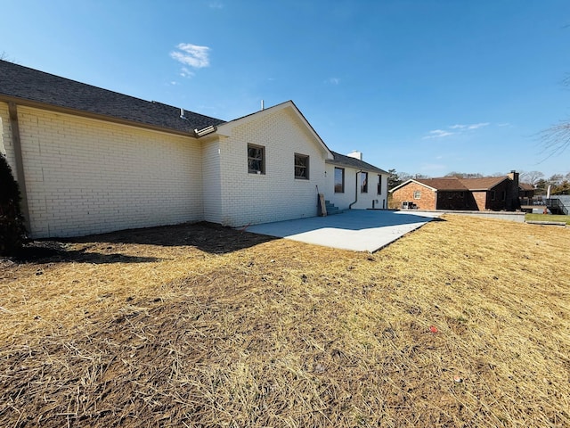 back of house featuring a patio, a yard, and brick siding