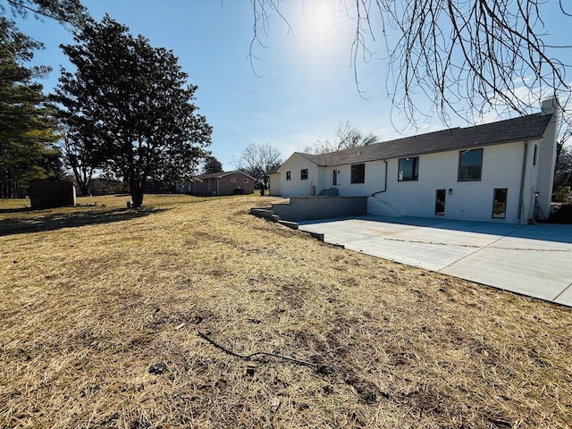 rear view of property with a patio area, a lawn, and brick siding