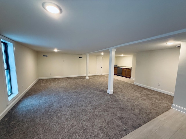 basement featuring light wood finished floors, plenty of natural light, light colored carpet, and baseboards