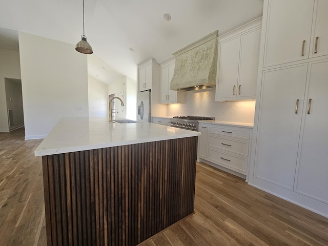 kitchen with premium range hood, a sink, wood finished floors, stainless steel appliances, and lofted ceiling