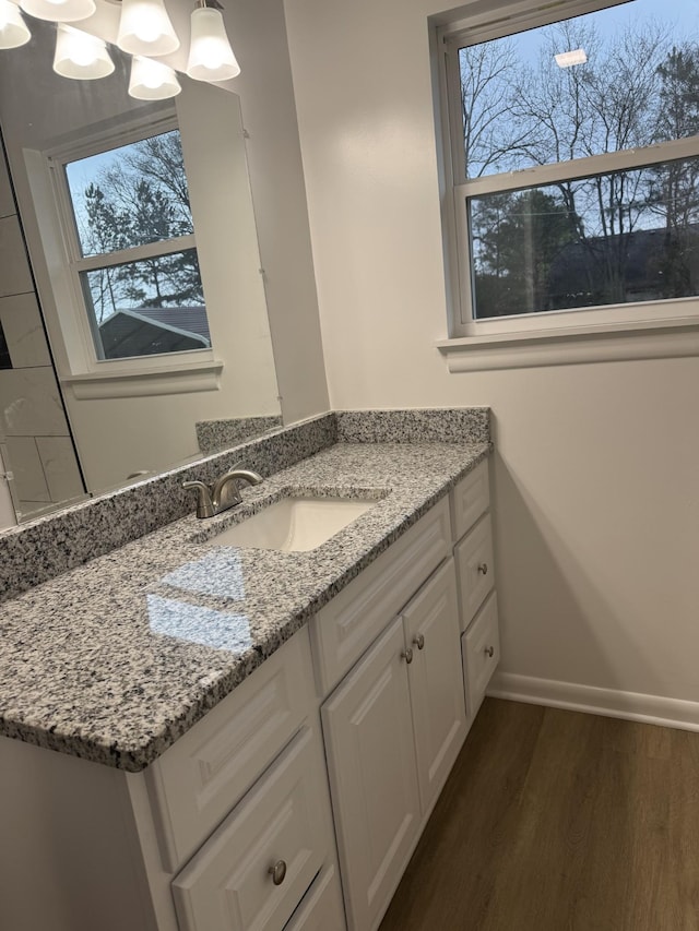 bathroom with hardwood / wood-style flooring, vanity, a chandelier, and a wealth of natural light