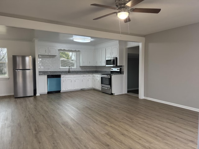 kitchen with sink, hardwood / wood-style flooring, stainless steel appliances, decorative backsplash, and white cabinets