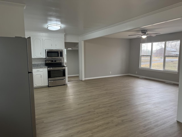 kitchen with hardwood / wood-style flooring, ceiling fan, appliances with stainless steel finishes, white cabinets, and decorative backsplash