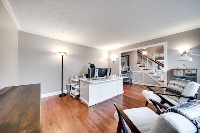 living room with hardwood / wood-style flooring, ornamental molding, and a textured ceiling