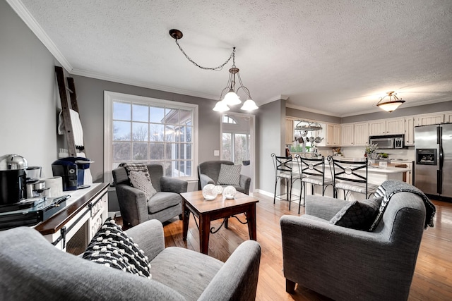 living room featuring a notable chandelier, ornamental molding, a textured ceiling, and light wood-type flooring