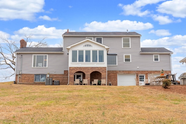 rear view of property featuring a garage, a yard, and cooling unit