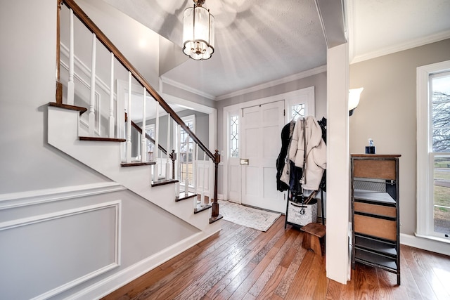 entrance foyer featuring wood-type flooring, a chandelier, and crown molding