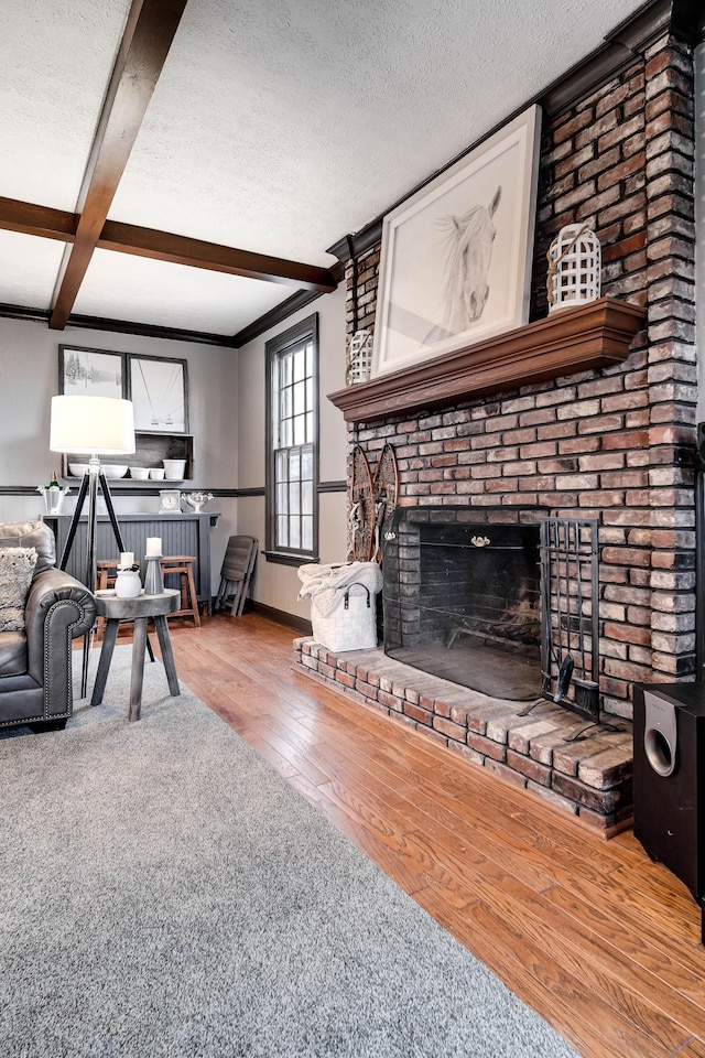 living room with beamed ceiling, a fireplace, hardwood / wood-style floors, and a textured ceiling