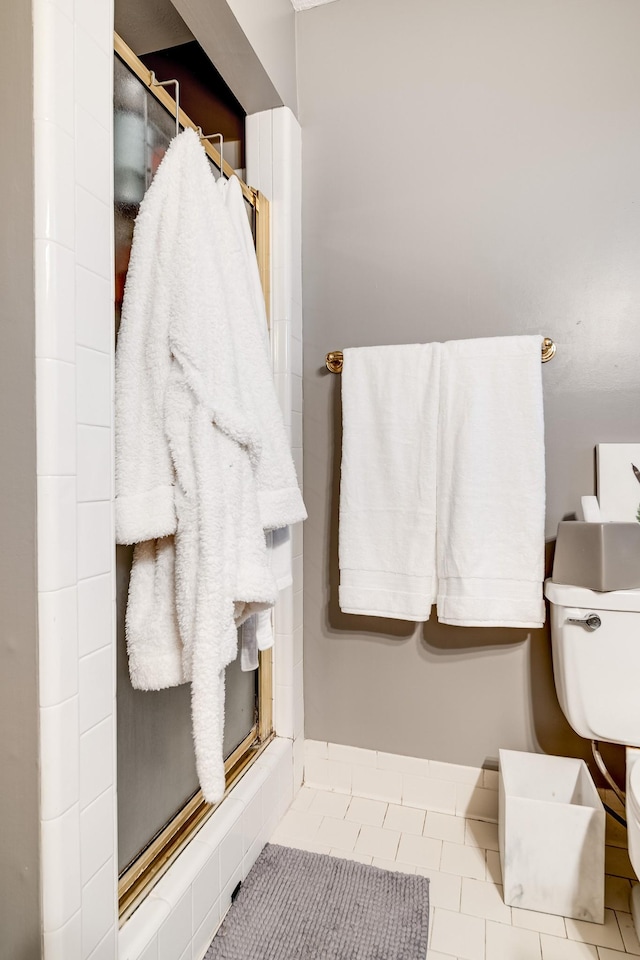 bathroom featuring a shower with shower door, tile patterned floors, and toilet