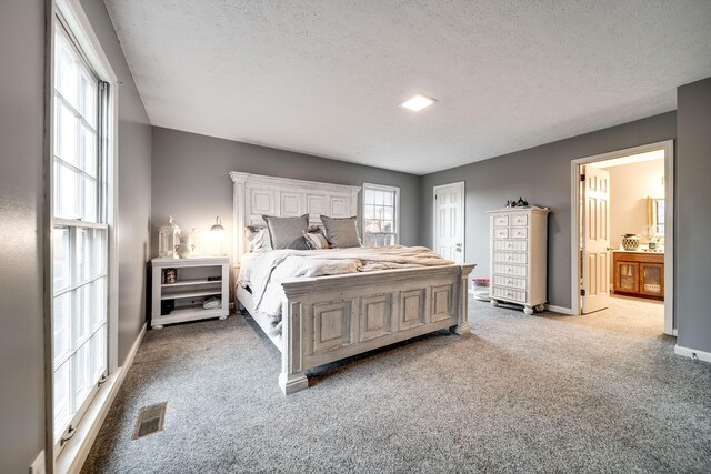 bedroom featuring connected bathroom, light colored carpet, and a textured ceiling