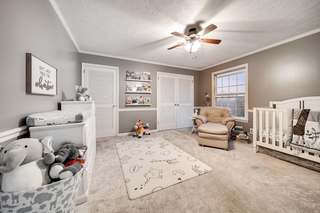 carpeted bedroom featuring multiple closets, ceiling fan, ornamental molding, and a textured ceiling