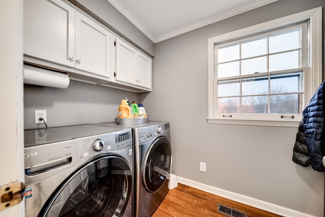 laundry area with cabinets, ornamental molding, washer and dryer, and light wood-type flooring