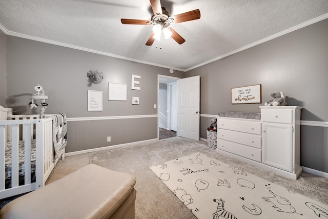 bedroom with crown molding, a nursery area, ceiling fan, and a textured ceiling