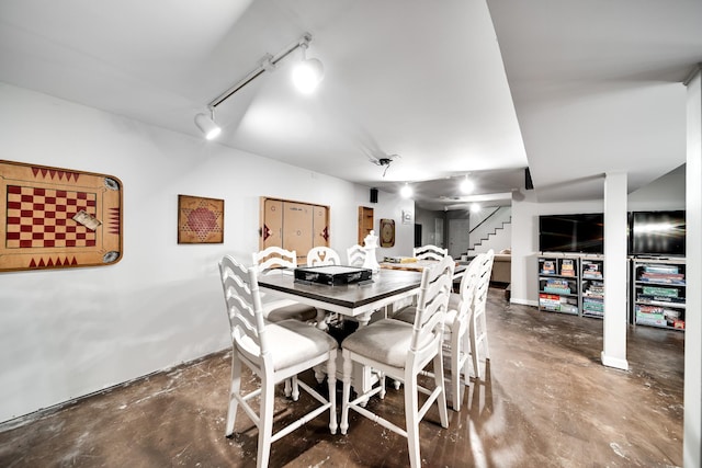 dining space featuring track lighting and concrete floors